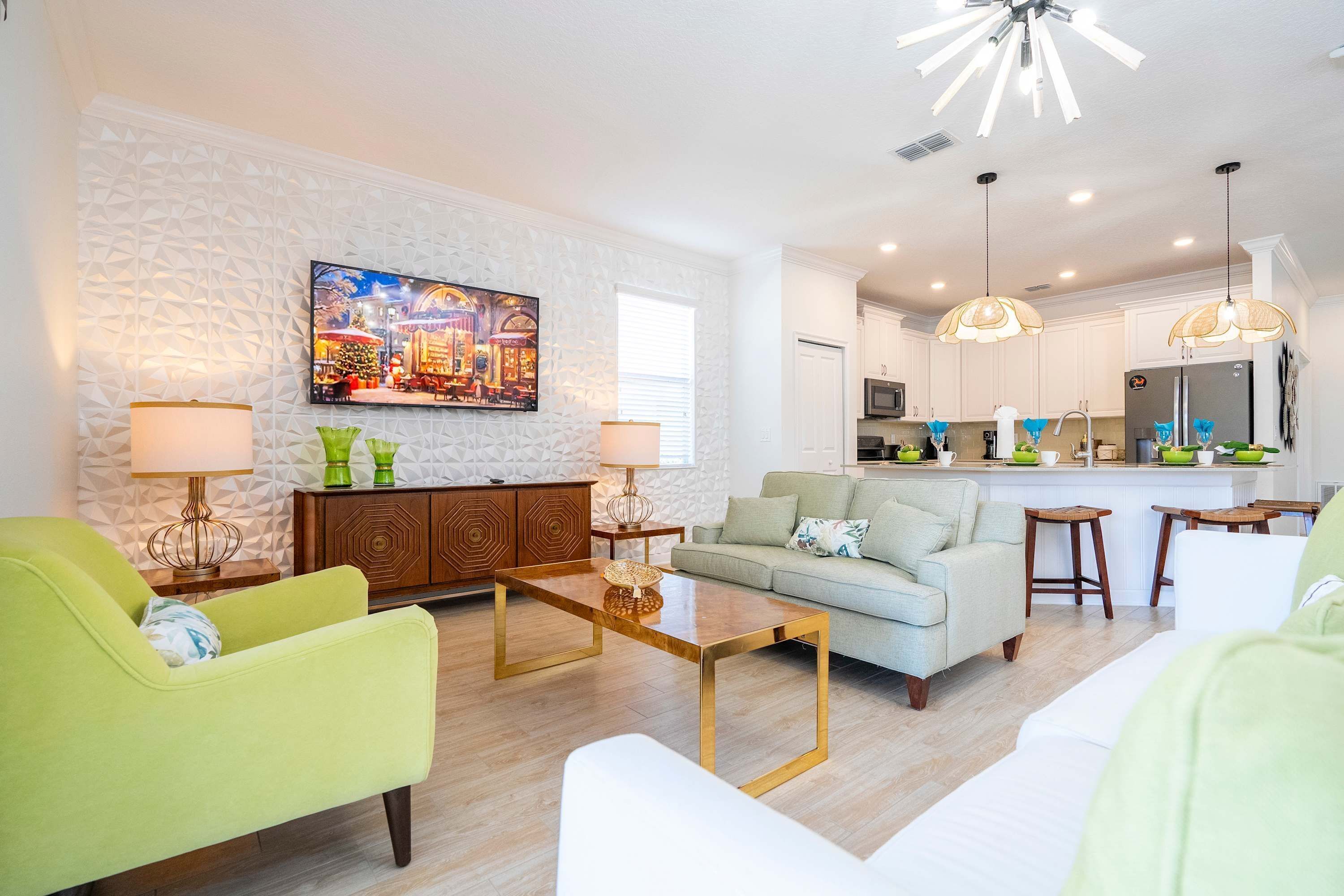 A modern living room with a sofa, armchairs, a coffee table, and a kitchen in the background.