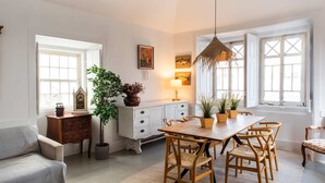 Un coin repas avec une table et des chaises en bois, un lustre et des plantes en pot.