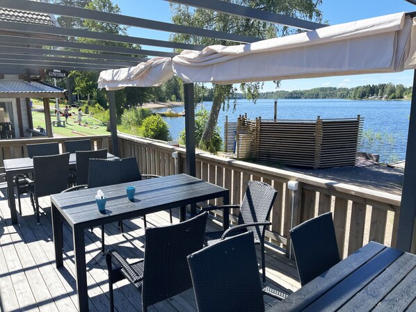A deck with outdoor seating, a view of a lake, and a sign reading 'ALPHYDDAN'.