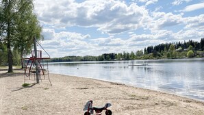 A lakeside park with a swing set, a seesaw, and a lifeguard tower.