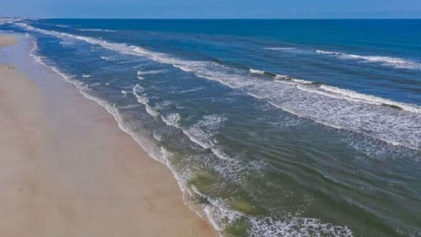 Ein Strand mit sanft anschwellenden Wellen.