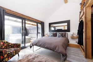 A bedroom with a bed, a chair, a large window, and a mirror on the wall. - Romantic Countryside Lodge With Hot Tub (Chichester)