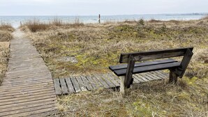 Un sendero de madera que lleva a un banco junto al mar.
