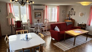 Una sala de estar acogedora con una mesa de comedor, sofá rojo y un mueble para televisión.