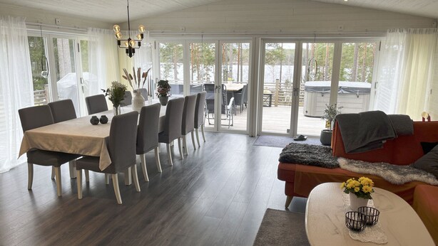 Een modern interieur met een eethoek, een bank en uitzicht door grote glazen deuren.