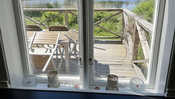 Una terraza con una mesa y sillas, con vista a un lago y un bosque.
