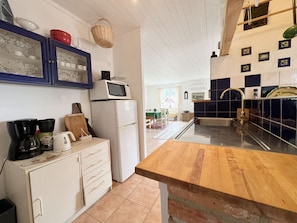 Une cuisine équipée d’un four à micro-ondes, d’un réfrigérateur, d’un plan de travail en bois et de placards.