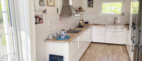A modern kitchen with white cabinets, a stainless steel range hood, and a window providing natural light.