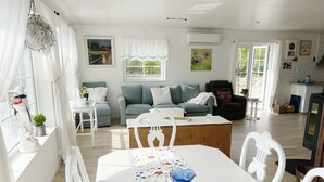 A spacious living room with a dining area, a sofa set, and a kitchen in the background.