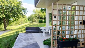 An outdoor patio area with a seating arrangement, a wooden trellis, and potted plants. - Modern apartment in the center of Visby | SE12053 (Visby)