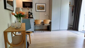 A modern living room with a wooden dining table, two chairs, a coffee machine, and a TV. - Modern apartment in the center of Visby | SE12053 (Visby)