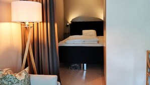 A hotel room with a bed, a nightstand, a lamp, and a curtain. - Modern apartment in the center of Visby | SE12053 (Visby)
