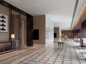 Eine moderne Hotelhalle mit Marmorboden, einer Rezeption und einer Sitzecke.