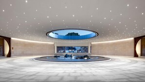 A spacious indoor area with a circular water feature in the center, a recessed ceiling with evenly spaced lights, and a large skylight above. - Dangkou Ancient Town Hotel Wuxi - Mgallery Collection (Wuxi)