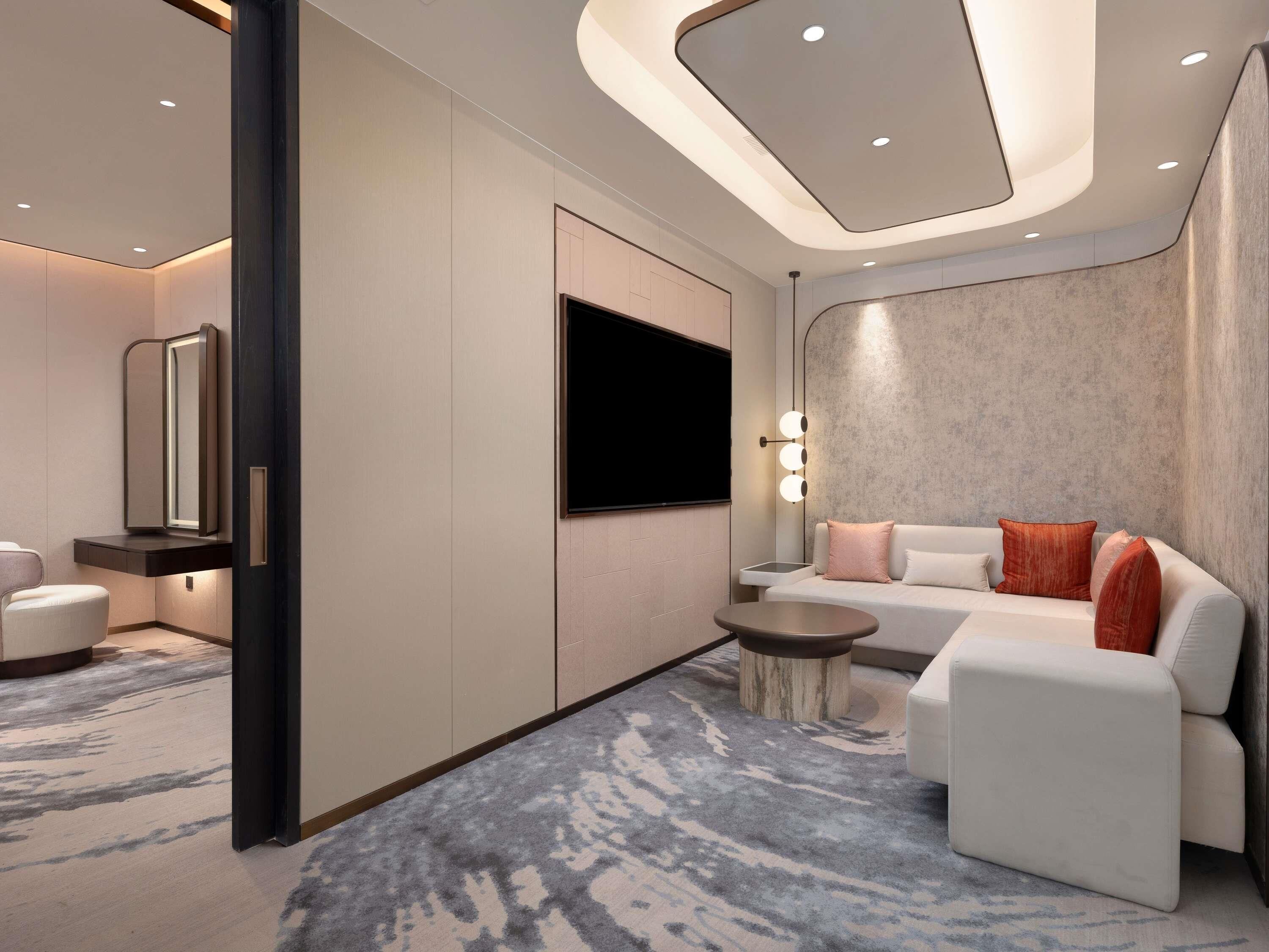 A modern living room with a sofa, a TV, a mirror, and a small table.