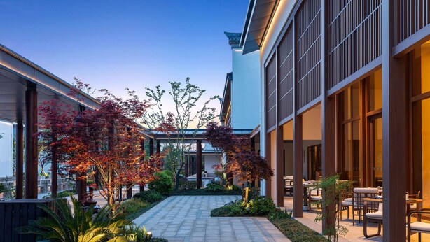 A modern building with a covered outdoor seating area, a paved walkway, and various plants. - Dangkou Ancient Town Hotel Wuxi - Mgallery Collection (Wuxi)