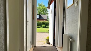 Un pasillo que lleva a una puerta con vistas a un jardín y una casa.