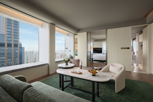A modern hotel room with a large window, a sitting area with a sofa and a small table, and a bedroom with a bed and a TV. - Fairmont Xiamen  (Xiamen)