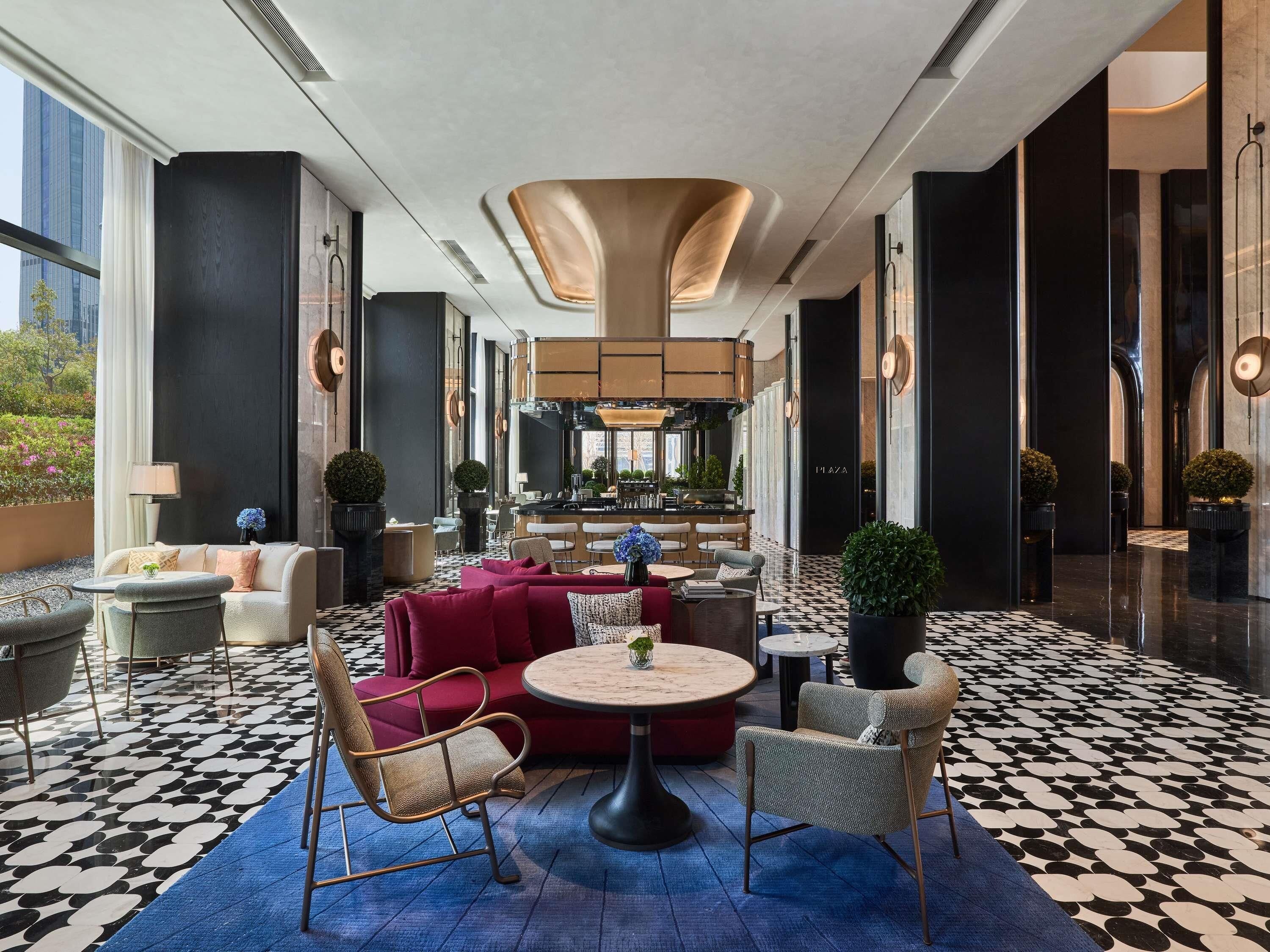 A spacious lobby with a checkered floor, seating areas, and a central bar.
