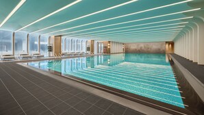 A modern indoor swimming pool with a long, narrow design, surrounded by lounge areas and large windows. - Fairmont Xiamen  (Xiamen)