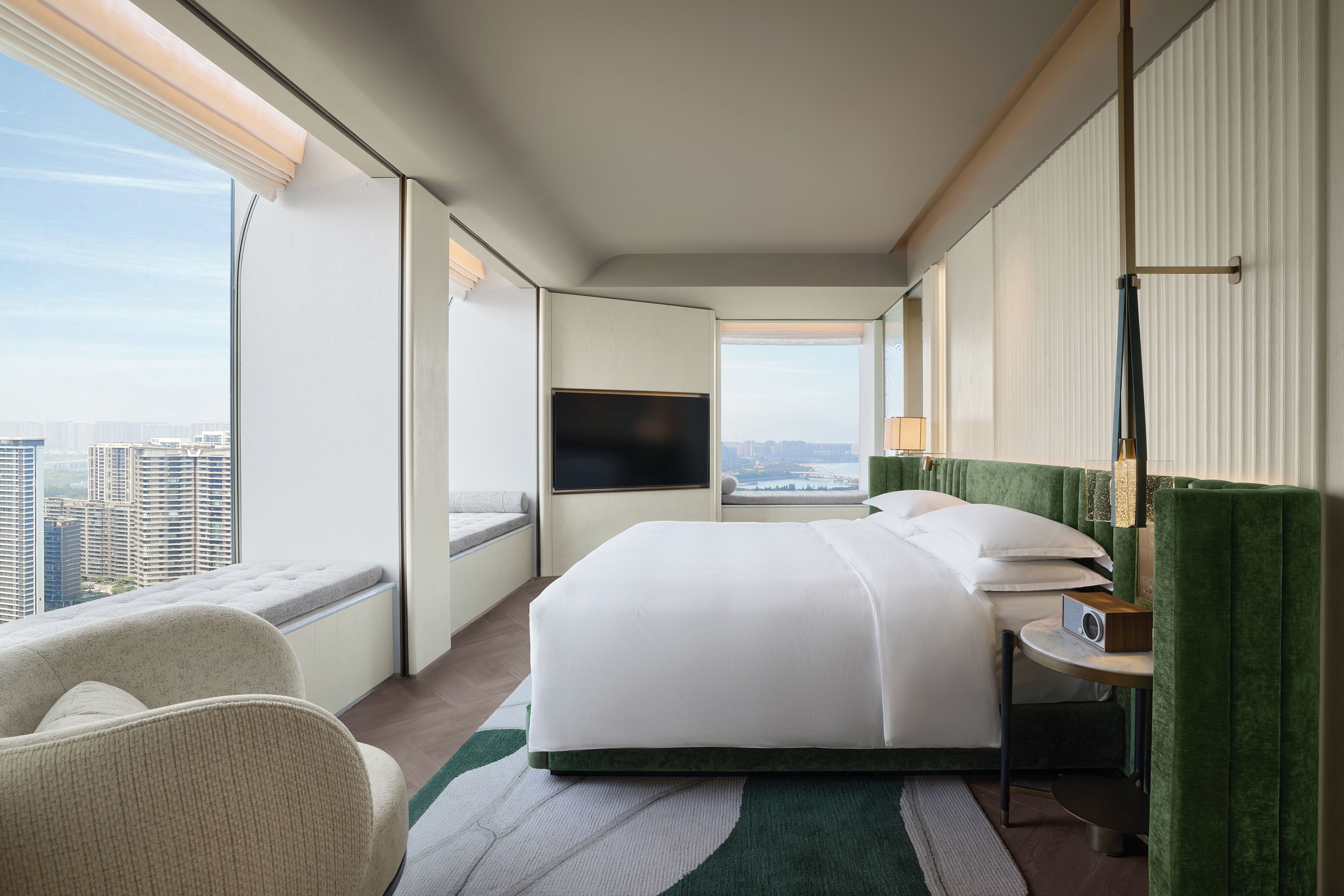 Une chambre d’hôtel dotée d’un grand lit, d’une télévision, d’un coin salon avec vue et d’une fenêtre donnant sur le paysage urbain.