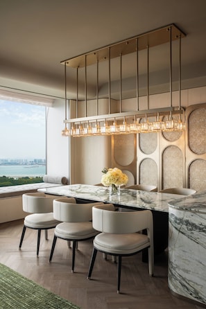 A modern dining area with a marble table, six chairs, a hanging light fixture, and a view of the cityscape. - Fairmont Xiamen  (Xiamen)