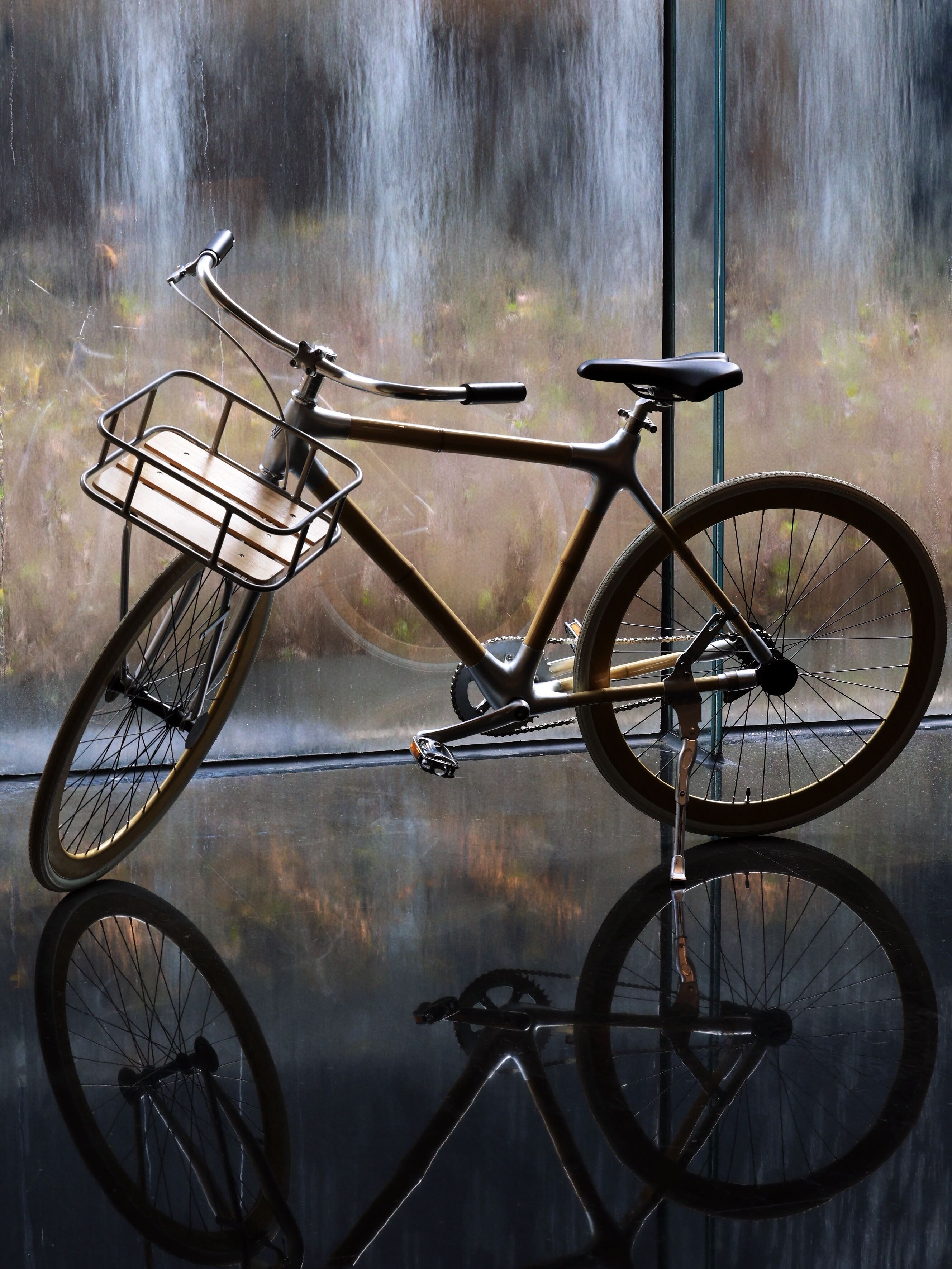 Un vélo avec un panier et une selle, appuyé contre une fenêtre d’où l’on peut voir une cascade.