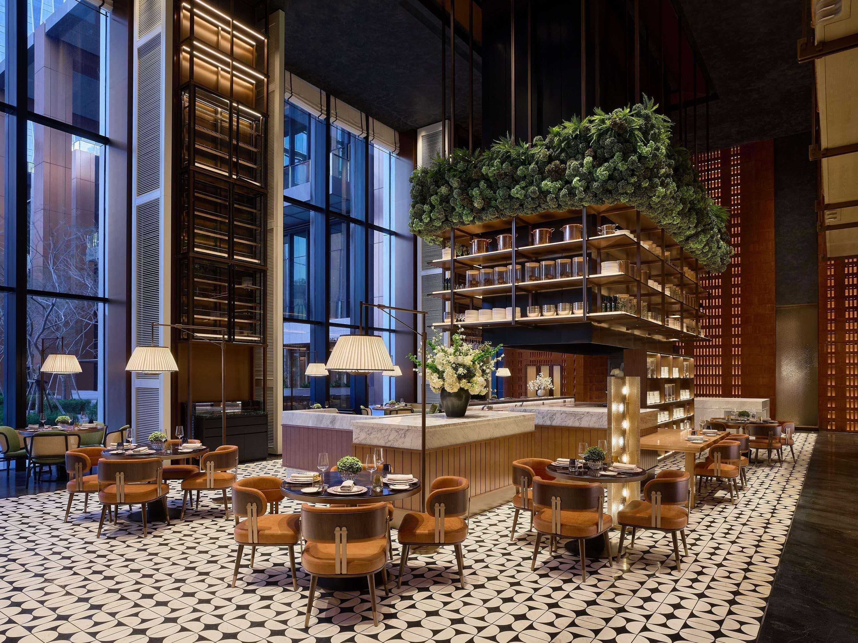 A modern interior with a central bar area, seating arrangements, and large windows.