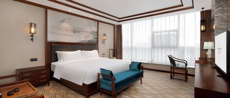 Een hotelkamer met een groot bed, een bank, een bureau en een televisie.