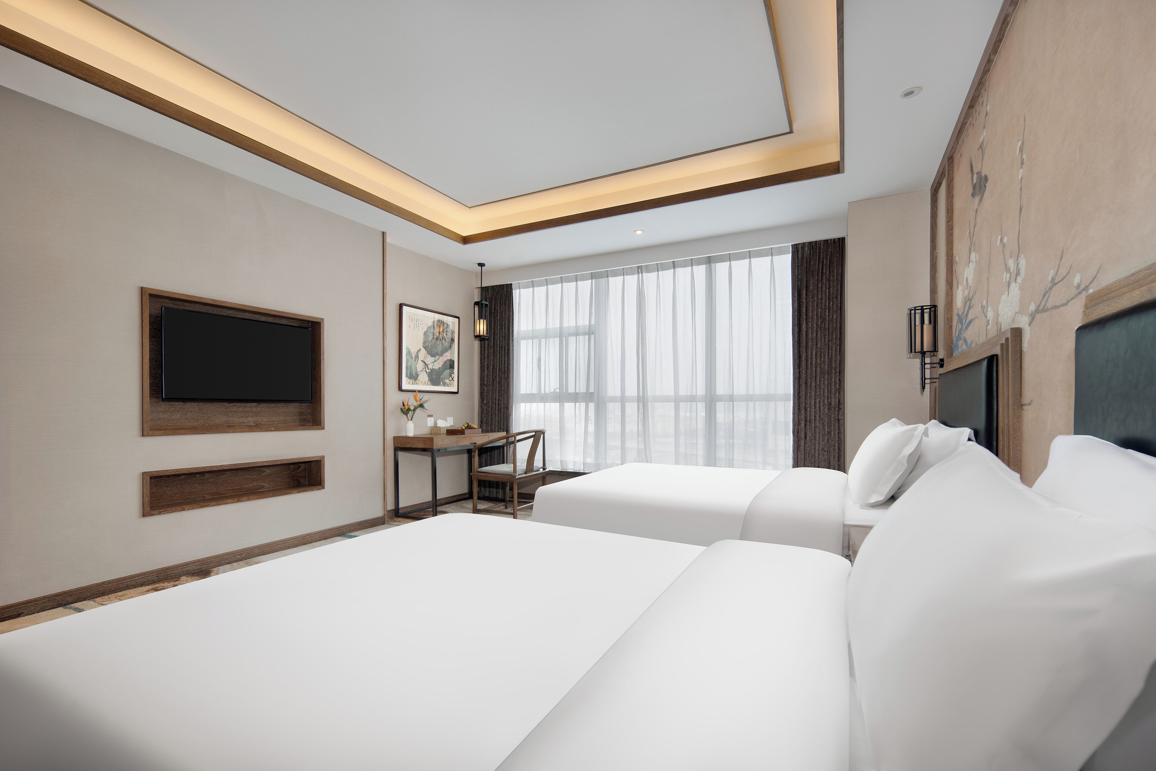 A modern hotel room with two beds, a desk, a flat-screen TV, and large windows.