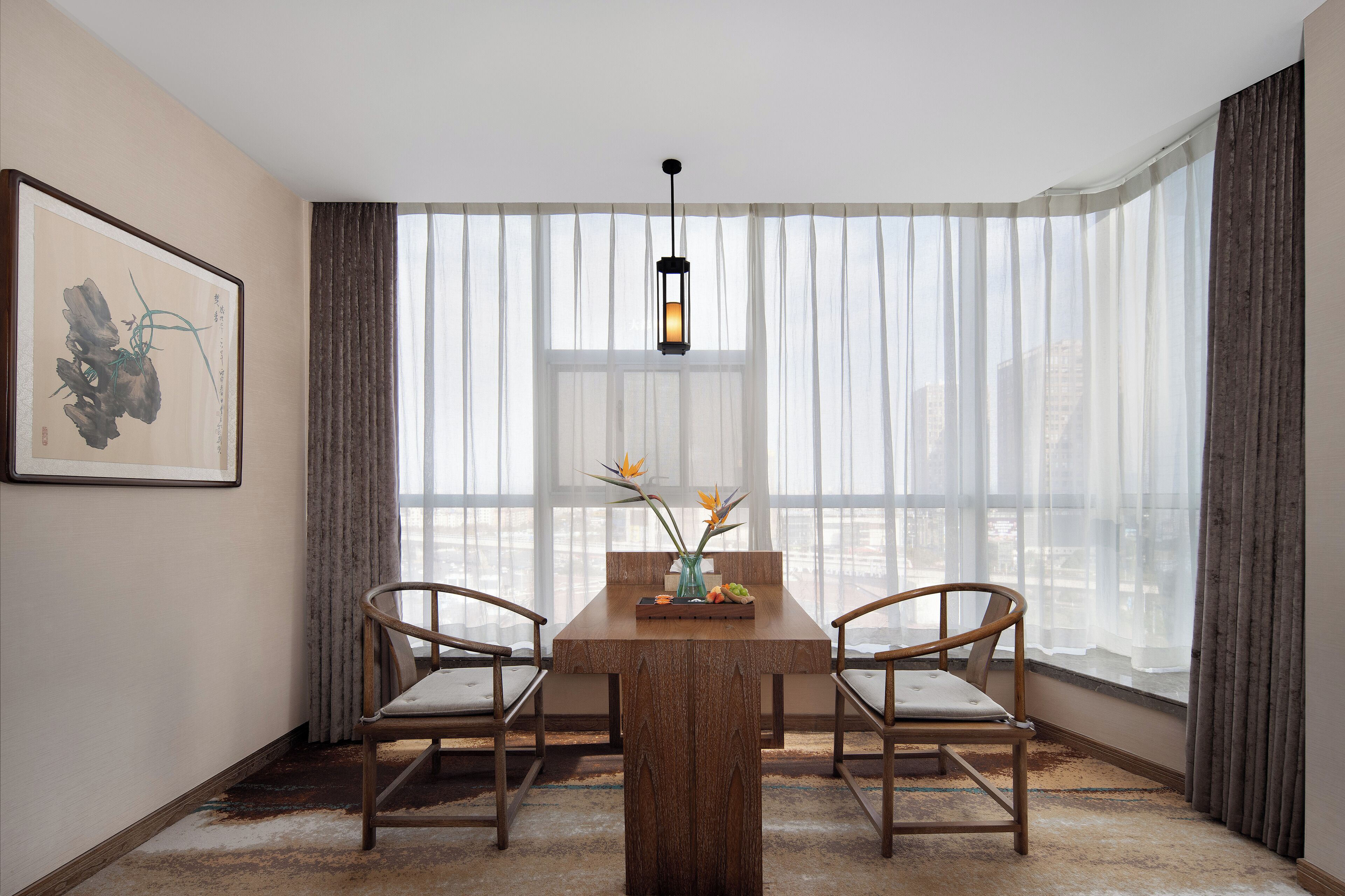 A dining area with a wooden table, two chairs, a vase with flowers, and a hanging lantern.