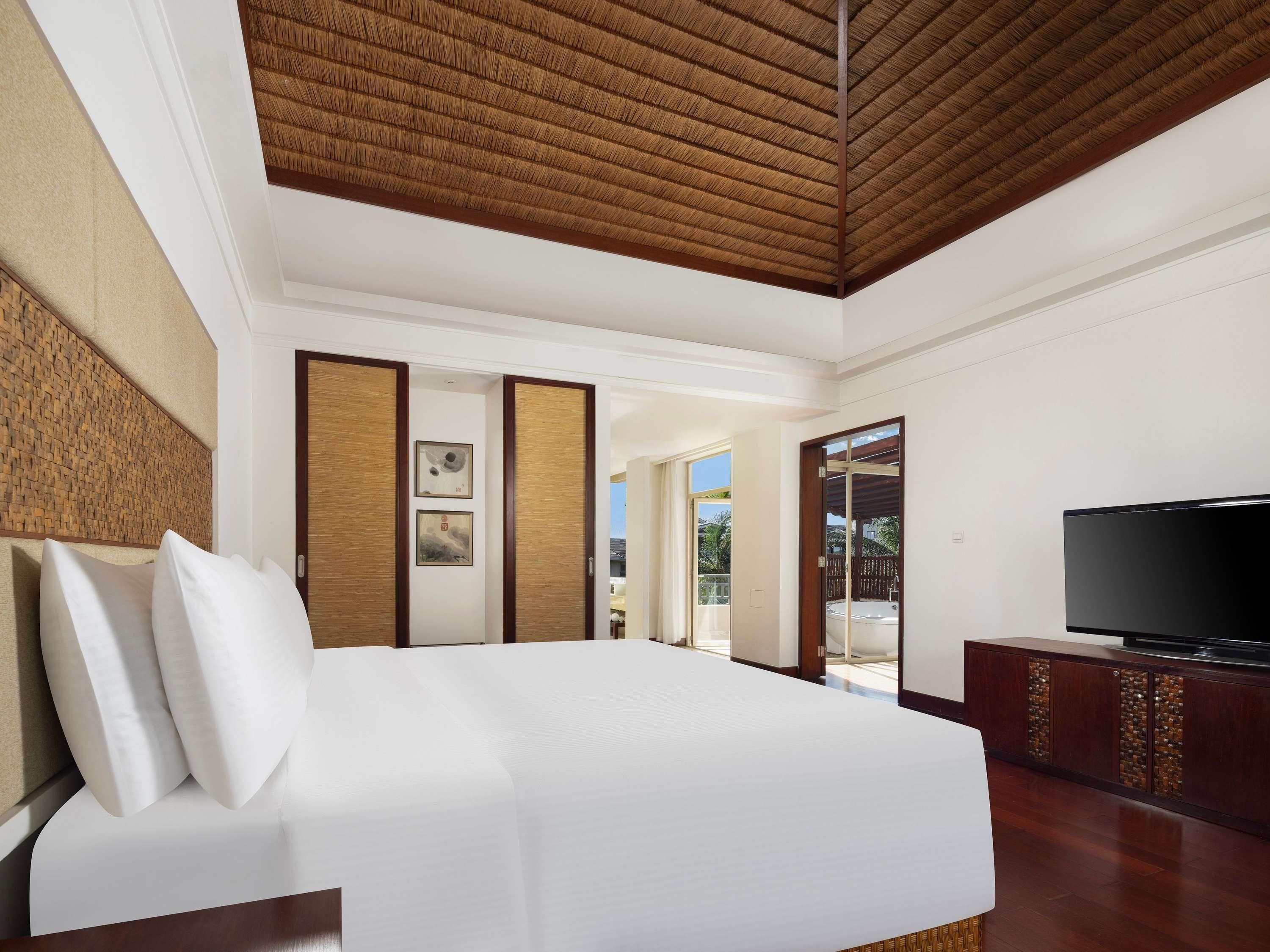A hotel room with a large bed, a television, and a view of the outdoors.