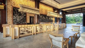 A spacious outdoor dining area with a long wooden table and chairs, a decorative wall with a mosaic pattern, and hanging pendant lights. - Grand Mercure Sanya Yalong Bay  (Sanya)