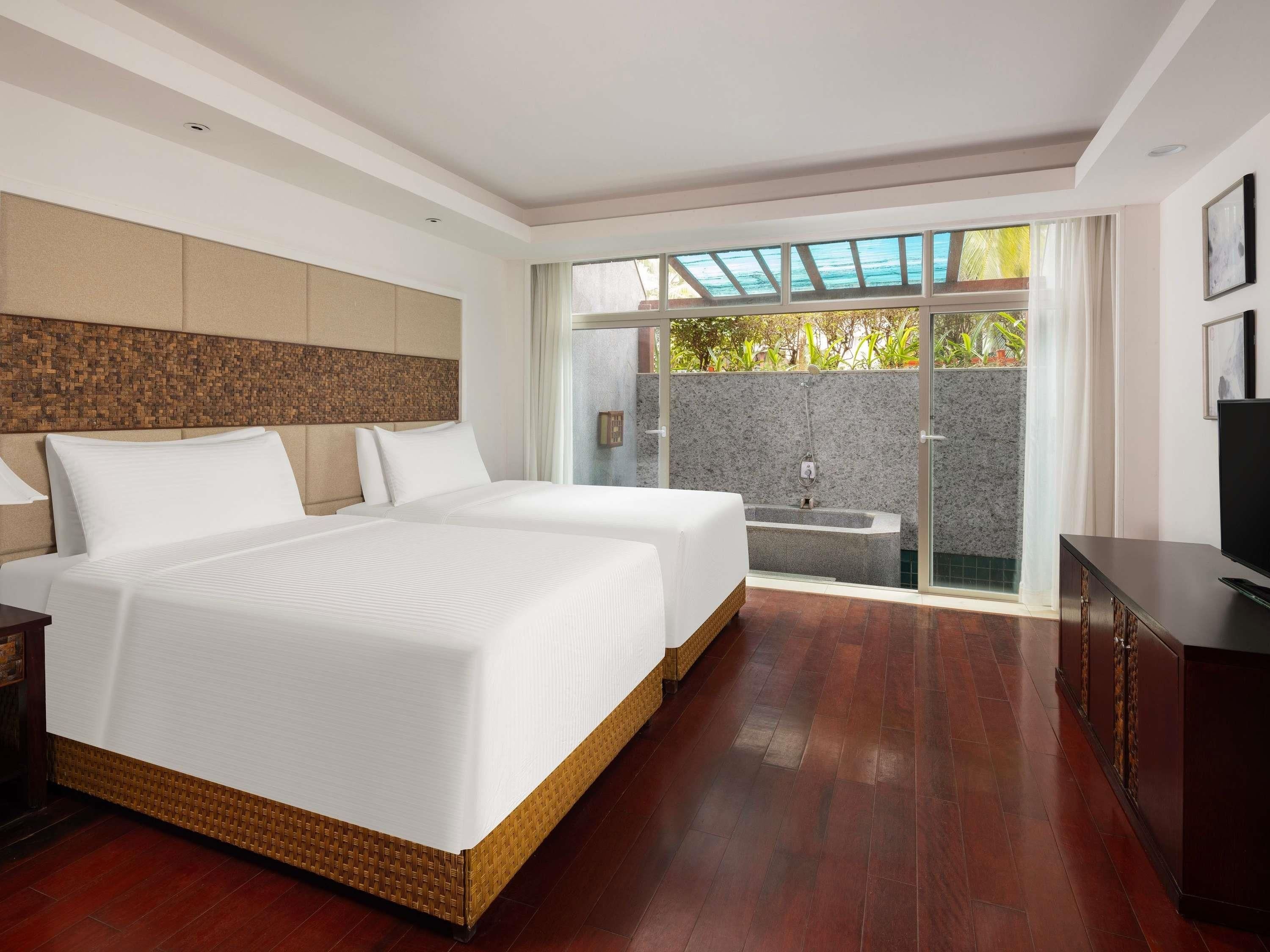 A hotel room with a large bed, a television, and a view of a pool and outdoor area.