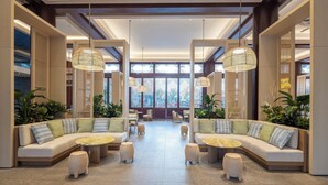A spacious lobby with a modern design, featuring a central seating area with sofas and round tables, large windows, and hanging pendant lights. - Grand Mercure Sanya Yalong Bay  (Sanya)