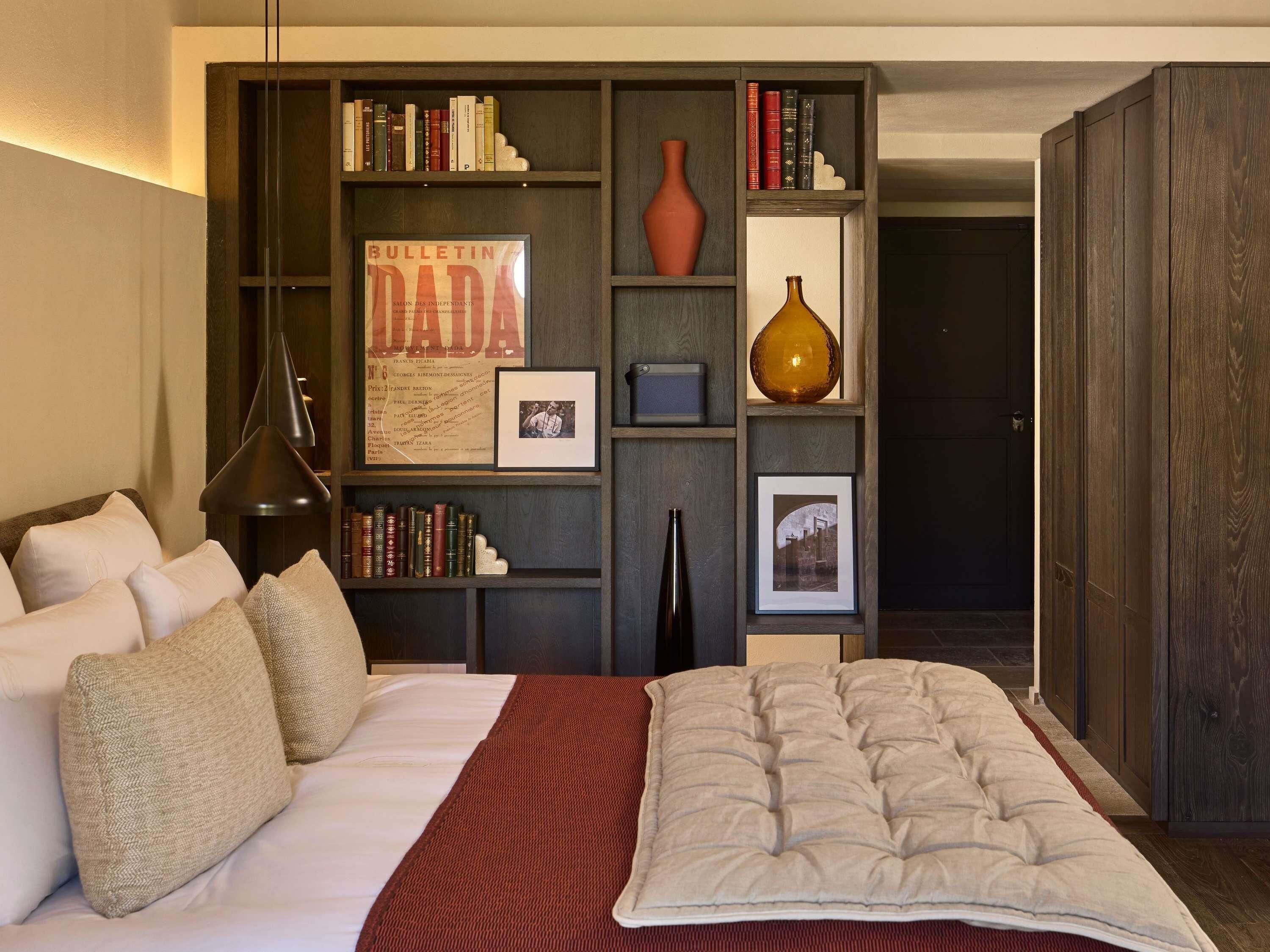 A bedroom with a bed, pillows, a bookshelf, and a framed bulletin board.