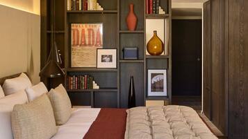 A bedroom with a bed, pillows, a bookshelf, and a framed bulletin board.