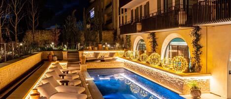 Una piscina al aire libre, sillones reclinables de piscina