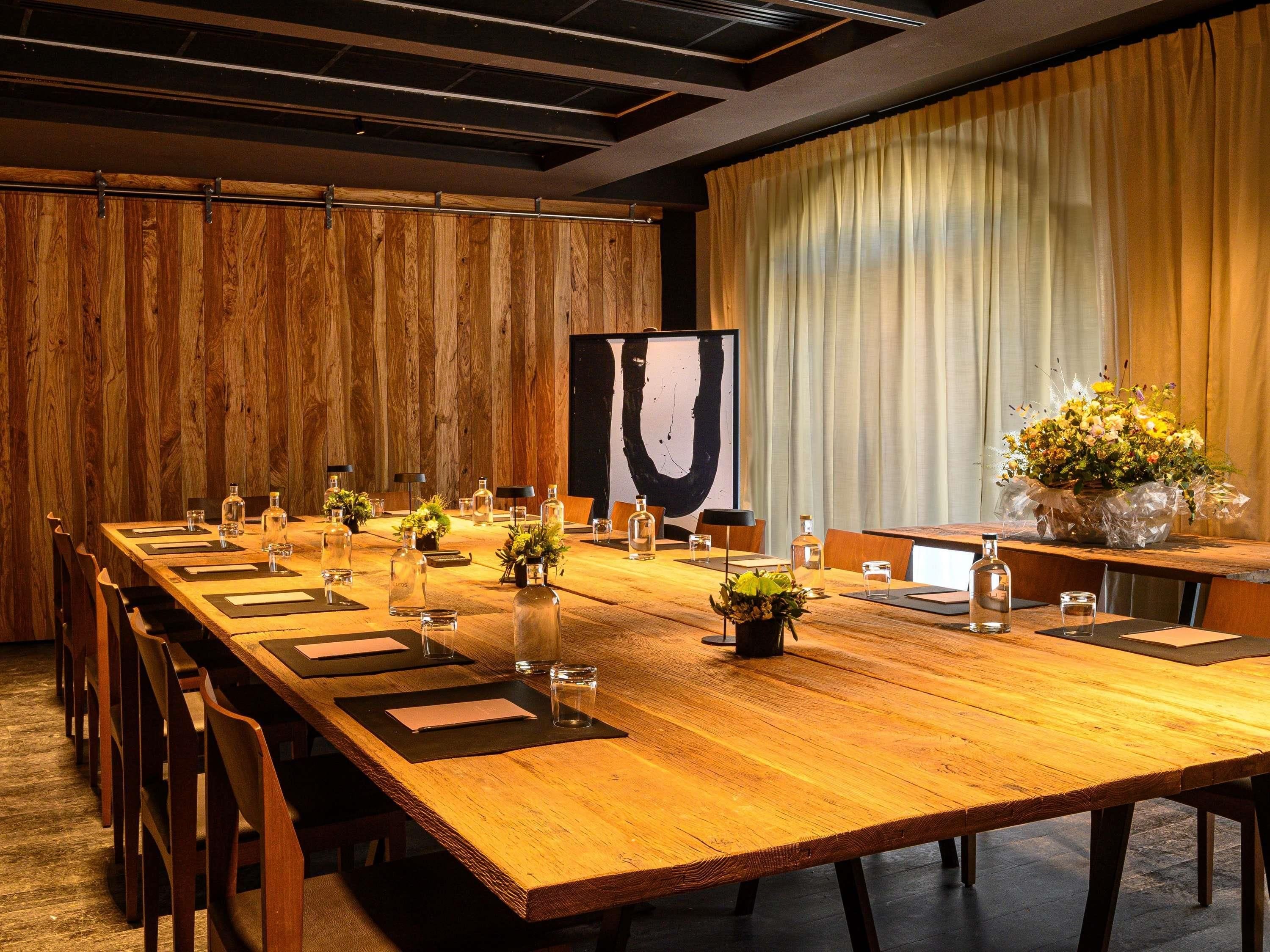 A conference room with a long wooden table, chairs, and a large abstract painting.