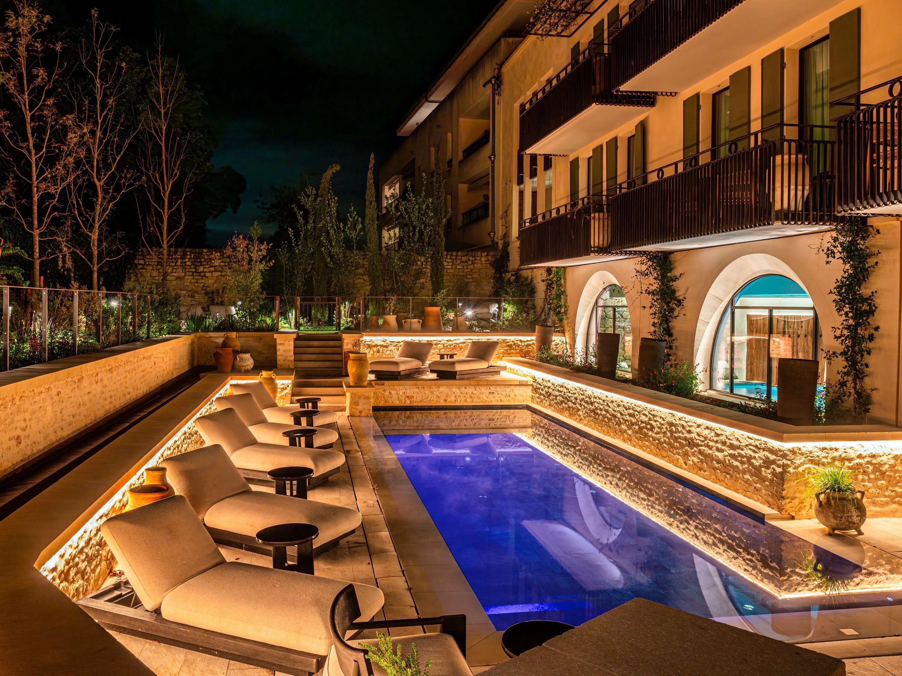 A pool area with lounge chairs and a stone wall.