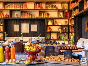 Ein gemütlicher Bibliotheksraum mit Bücherregalen, einem Couchtisch mit Snacks und einer Obstschale.