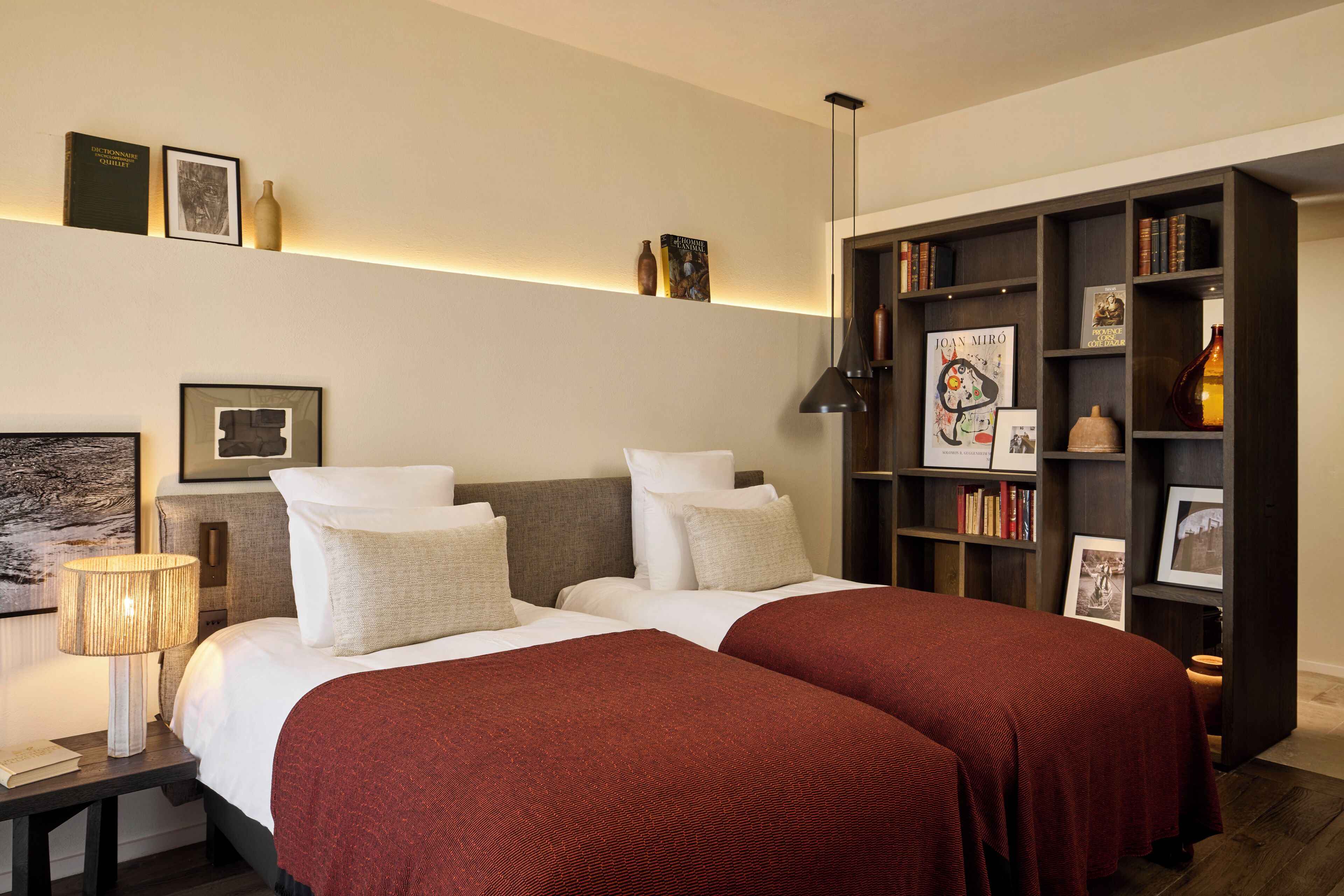 A bedroom with a large bed, bedside tables, a bookshelf, and a wall-mounted lamp.