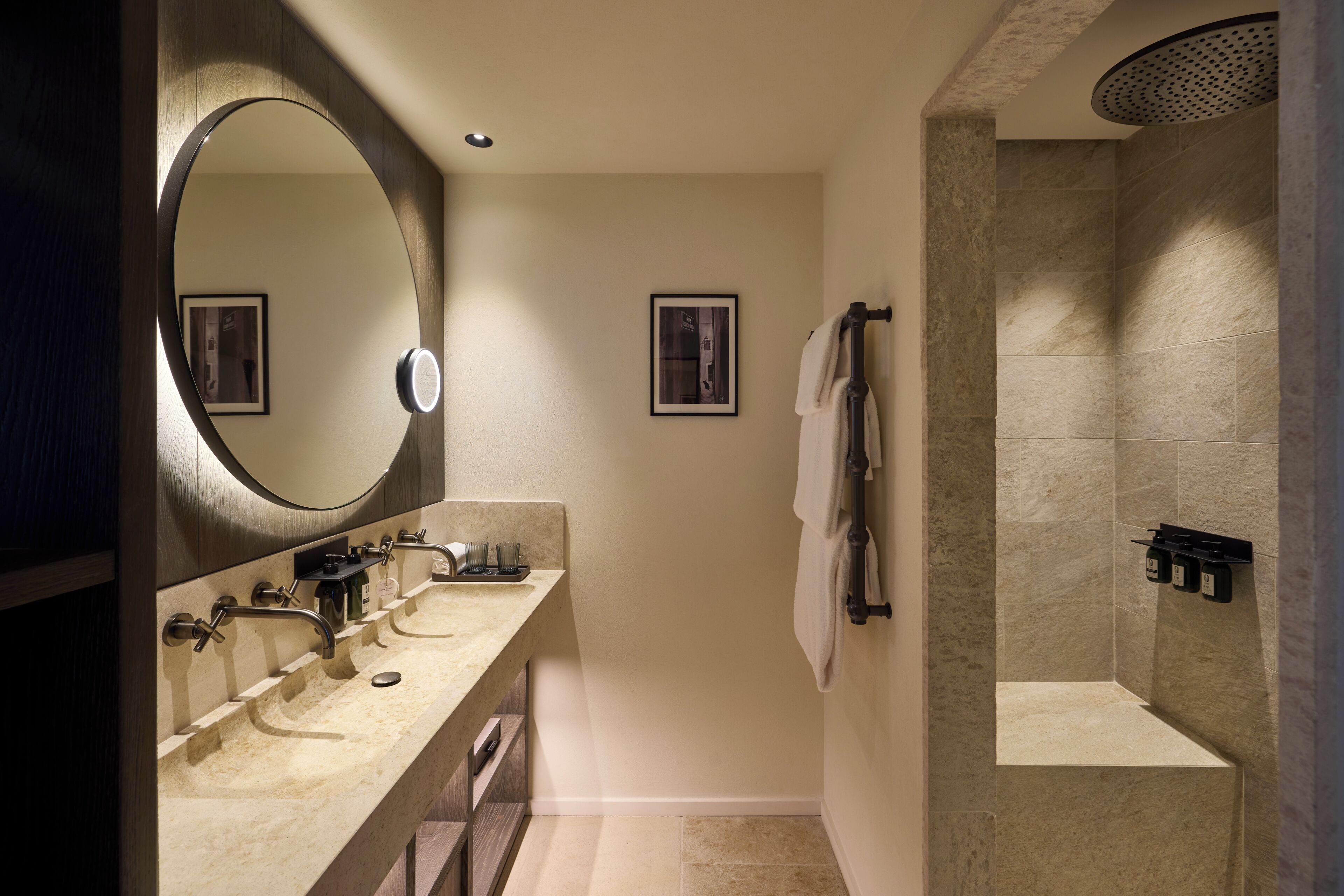 A modern bathroom with a large mirror, three sinks, a shower, and a towel rack.