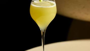 A cocktail in a martini glass with a lemon garnish on a table.
