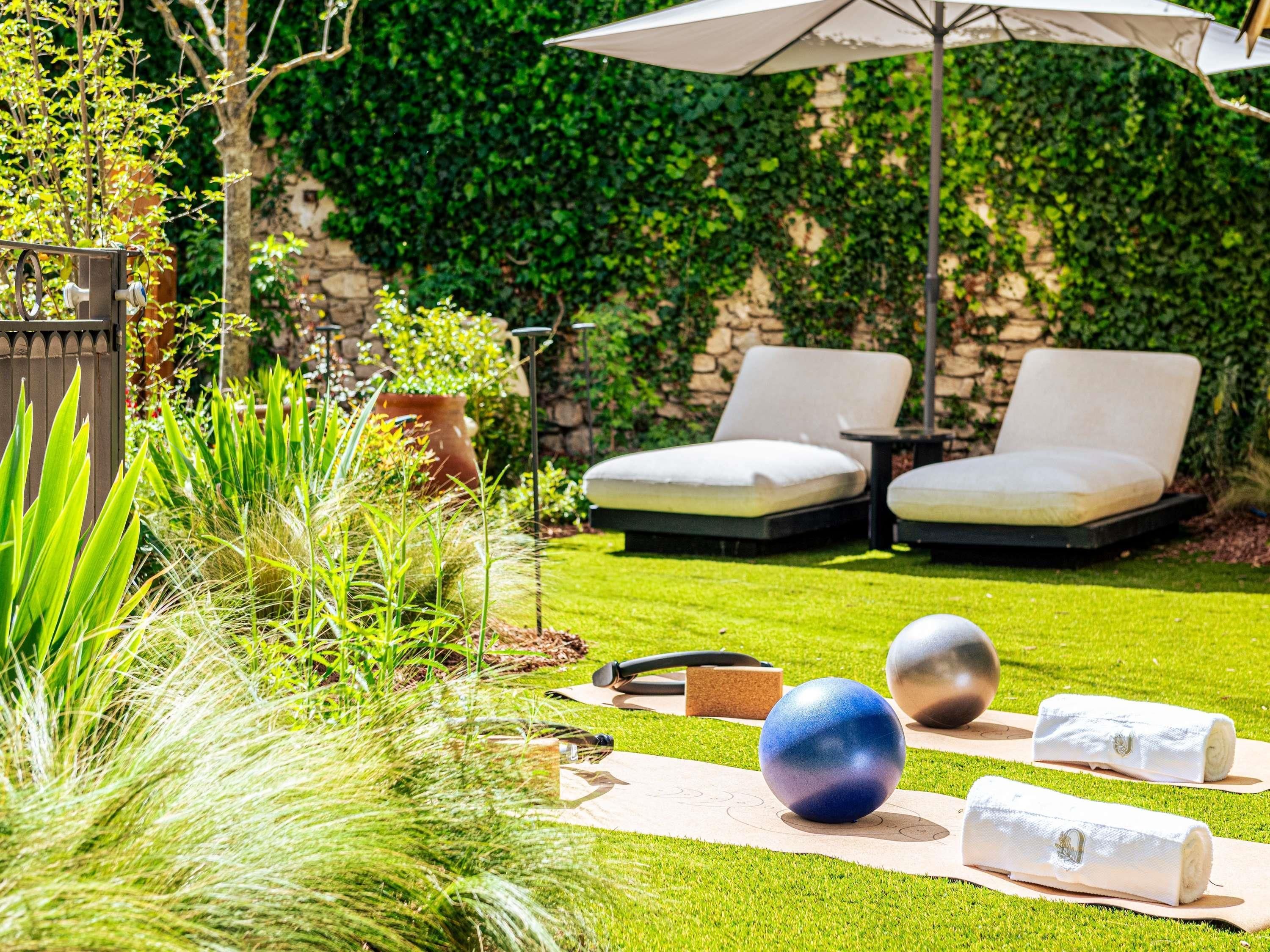 Un jardin avec une pelouse, deux chaises longues, une table et une pergola.