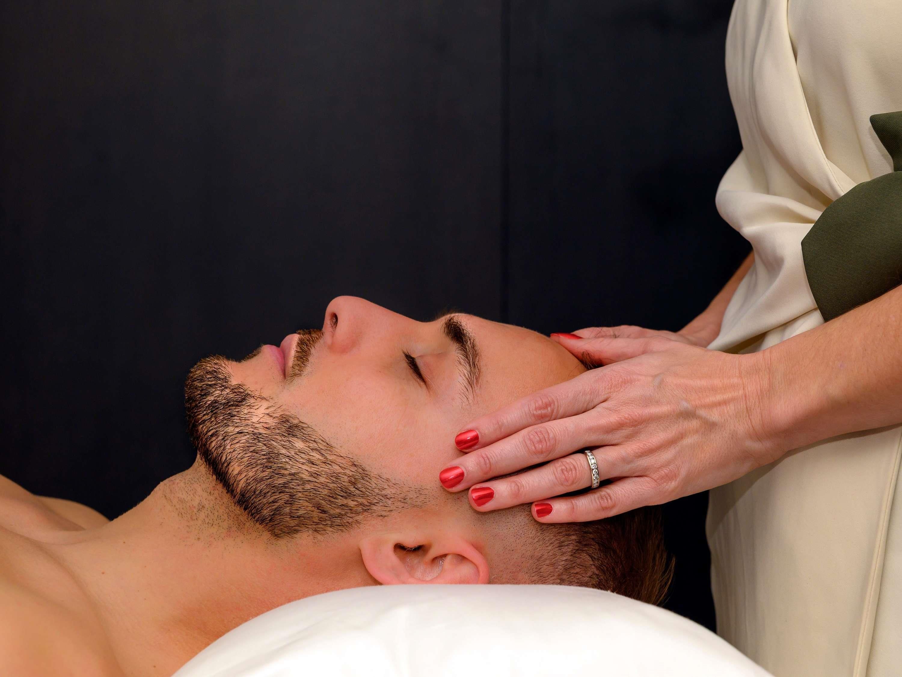 A person lying down with a hand on their head, suggesting a massage or relaxation service.