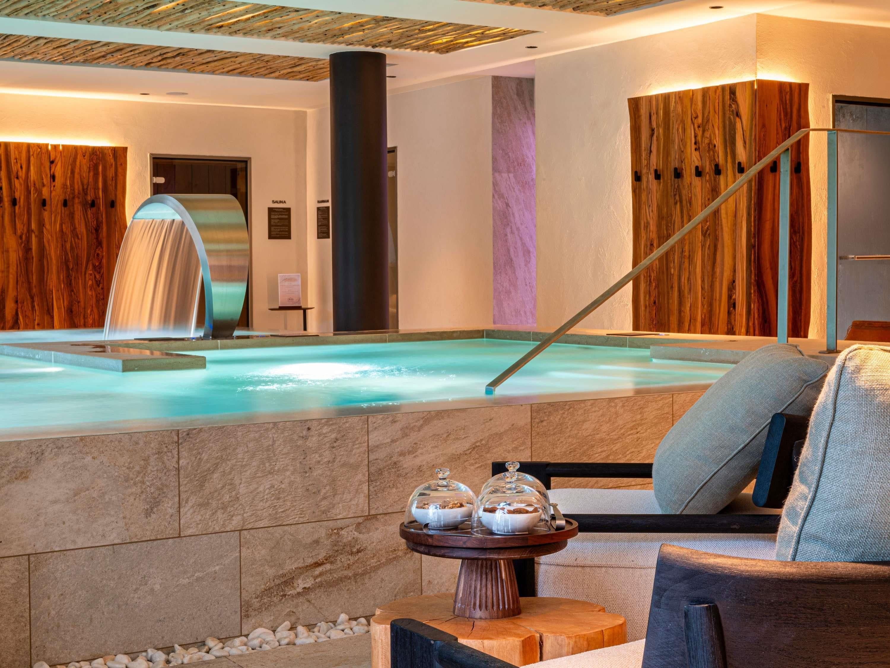 A spa area with a hot tub, wooden walls, and a seating area with a table and chairs.