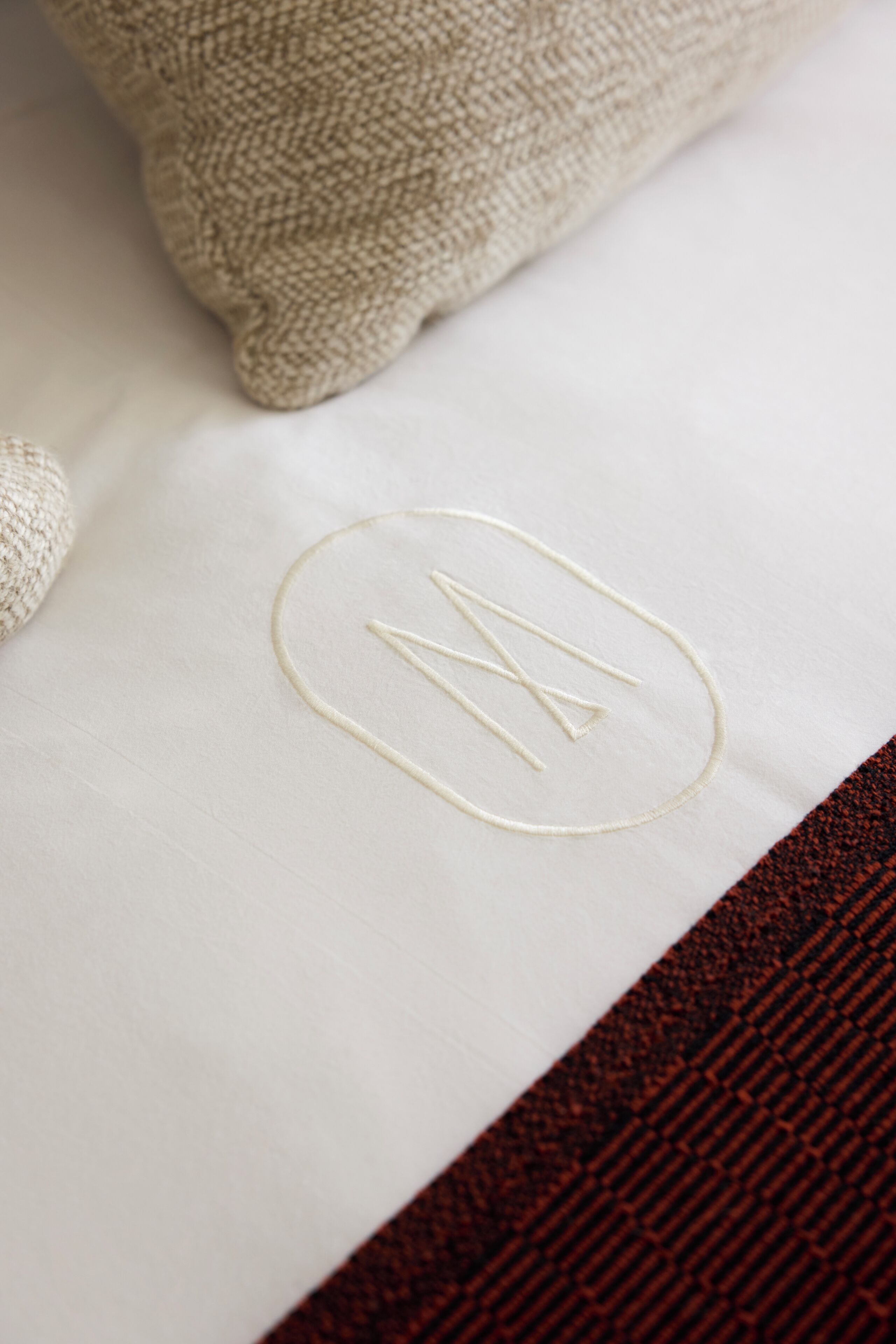A white pillow with a monogram embroidery.