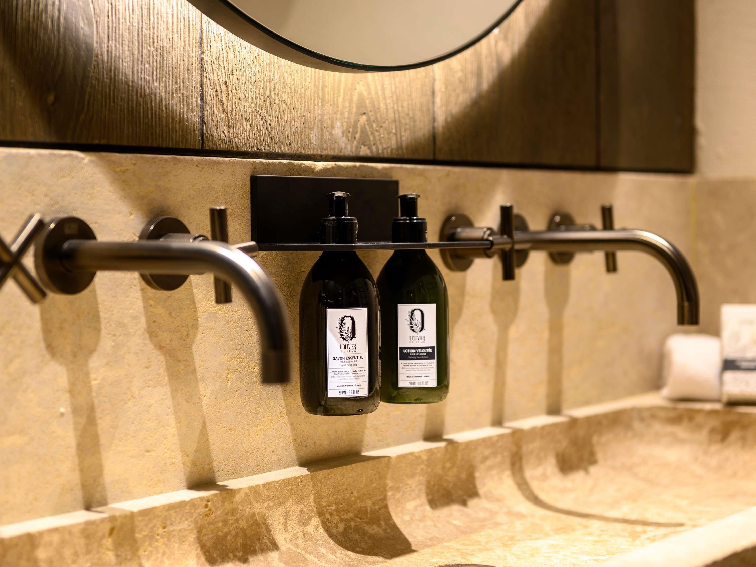 A bathroom with a built-in shelf holding two bottles of lotion and a towel dispenser.