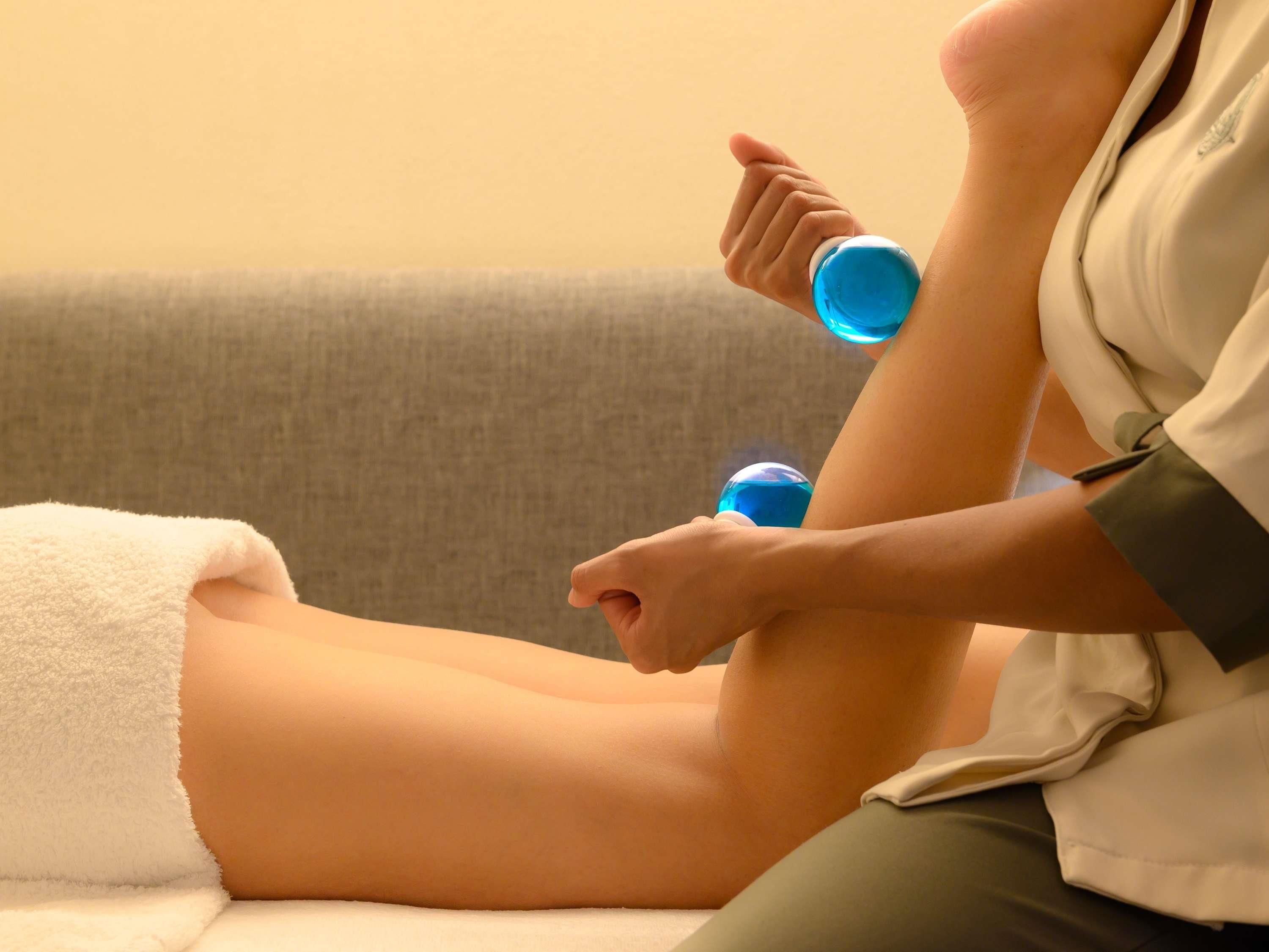 A person sitting on a couch with a white towel and a blue bottle.